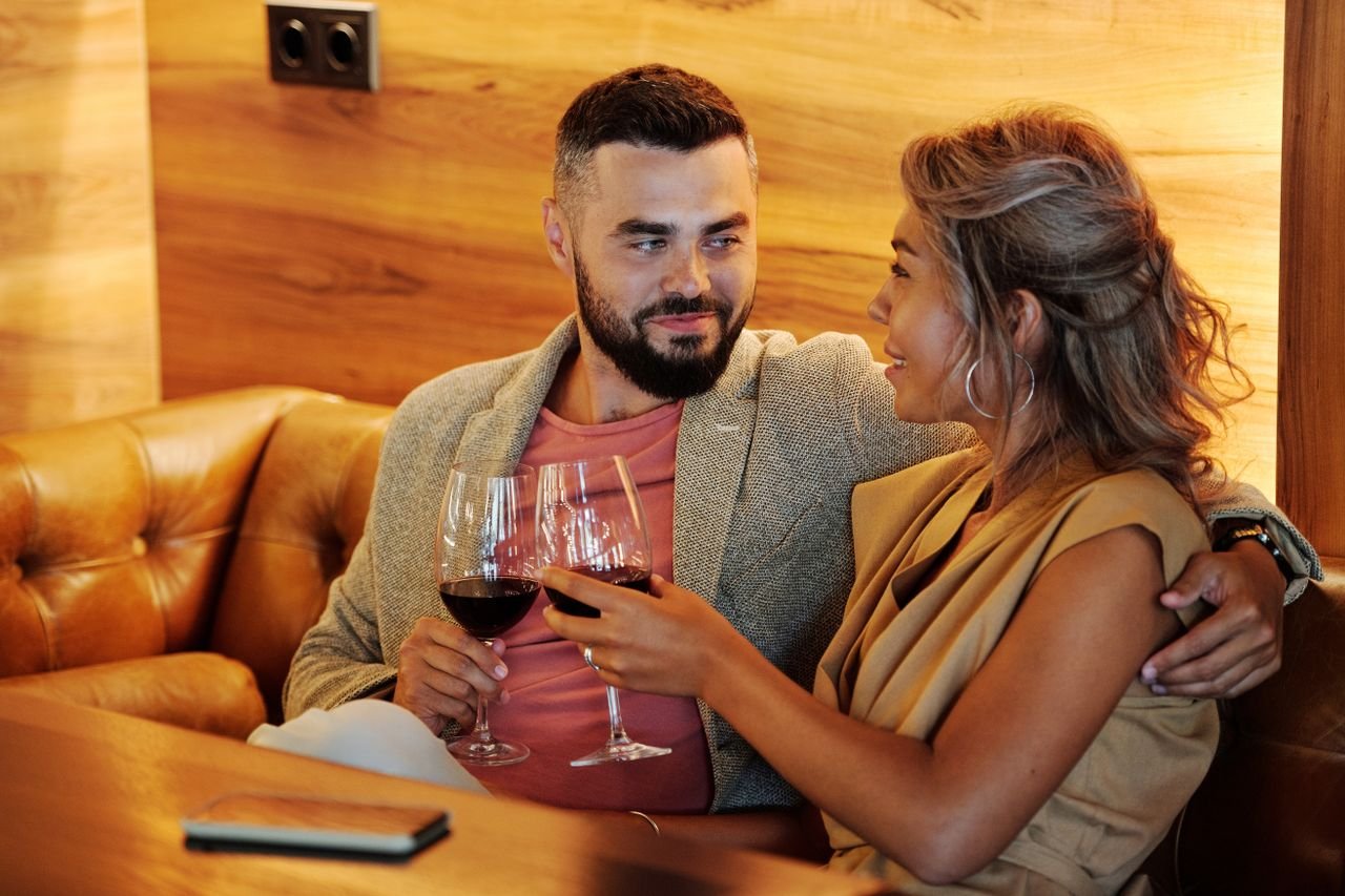 A couple enjoys a romantic evening with wine in a stylish indoor restaurant setting.