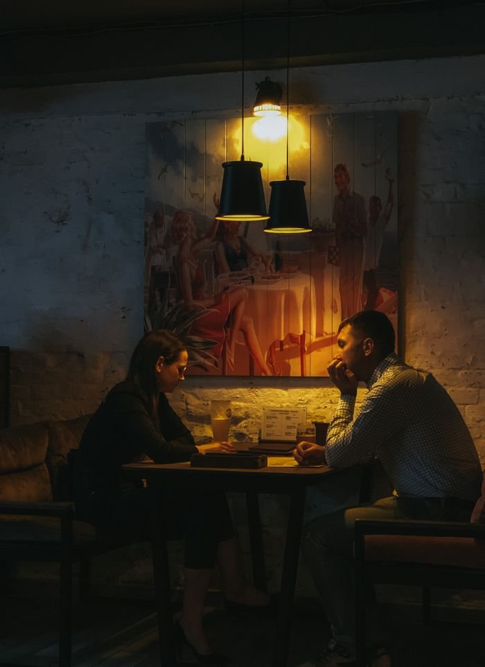 Couple enjoying a relaxed dinner under warm lighting in a cozy restaurant setting.